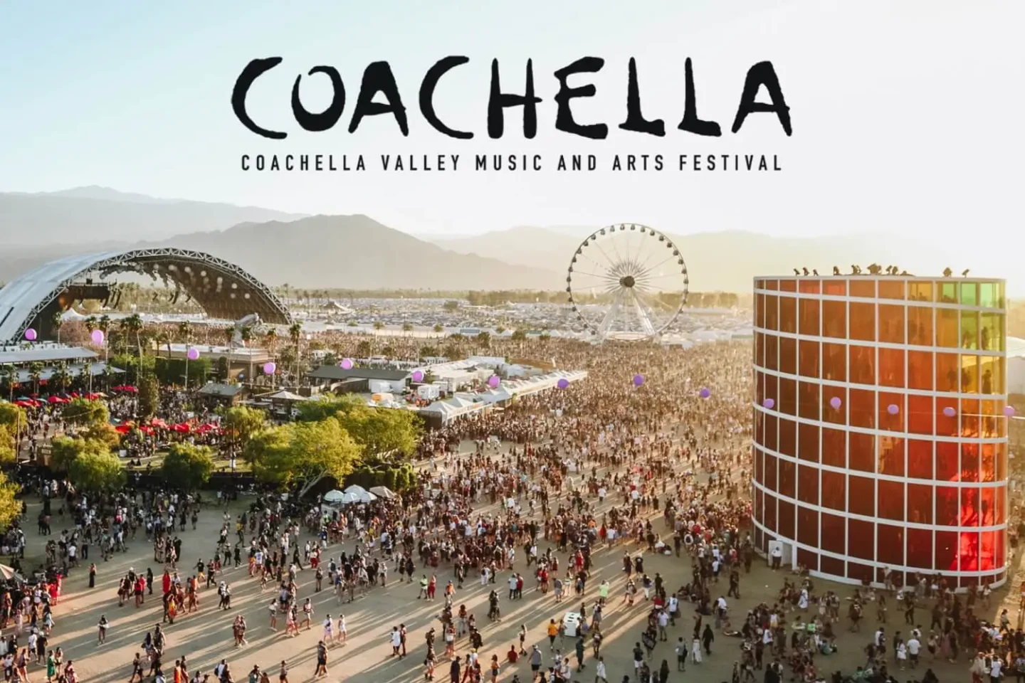 A large crowd gathers at the Coachella Valley Music and Arts Festival, with coachella branding visible on a Ferris wheel, stage, and art installation, all set against mountain views and a clear sky. The word Coachella appears at the top.