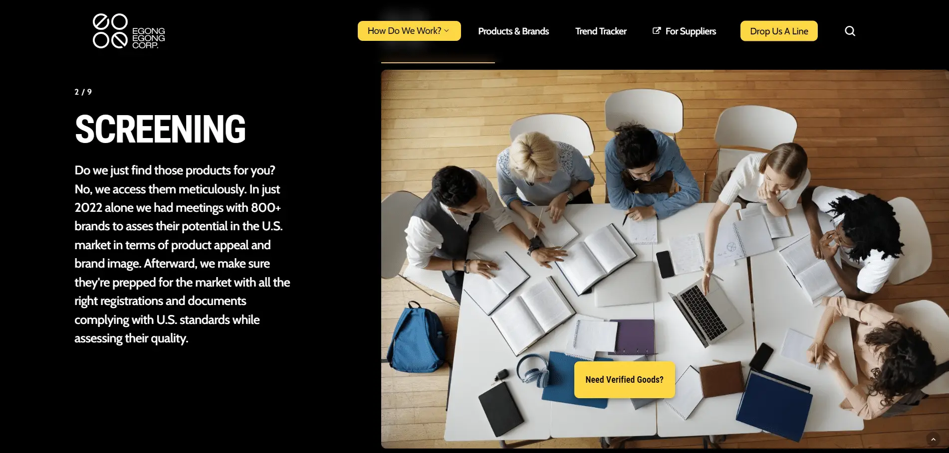 Egongegong-Portfolio-4 A group of five people sit around a table with open laptops, notebooks, and documents, collaborating on work. The photo is taken from above in a well-lit room with wood flooring.