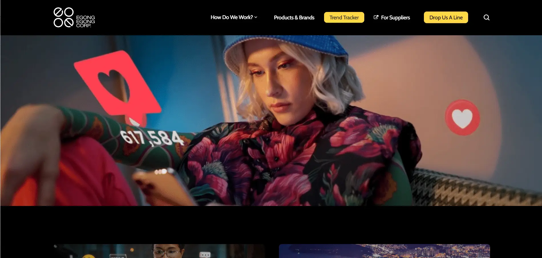 Egongegong-Portfolio-5 A woman in a blue hat and floral jacket looks at her phone, with a large social media heart icon and the number 617,584 superimposed, indicating likes. The website menu is visible across the top.