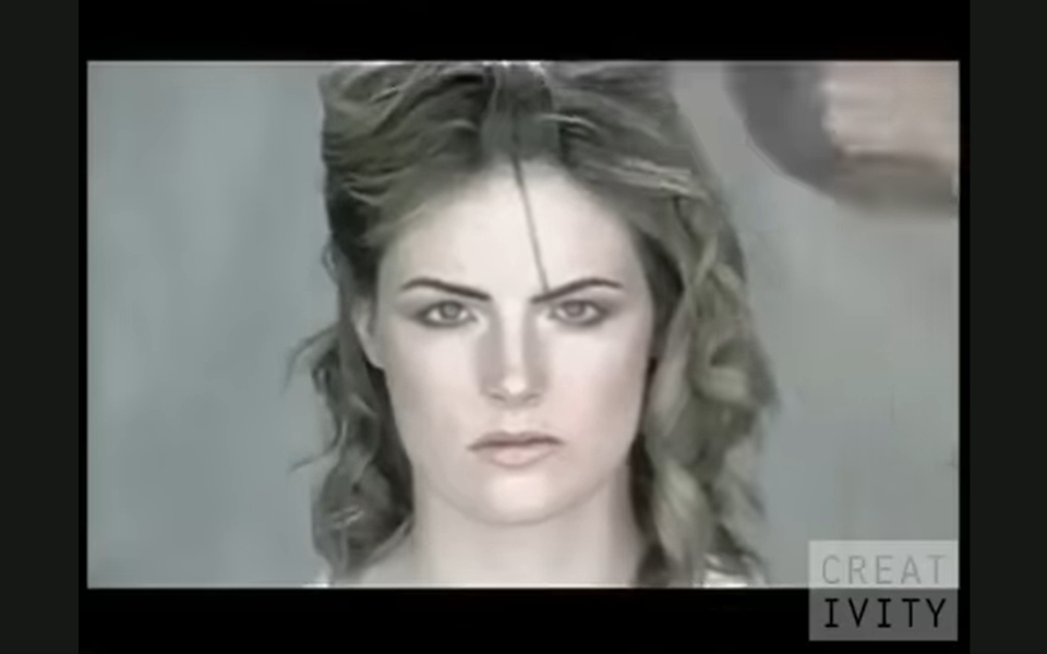 A woman with styled, wavy hair looks directly at the camera with a neutral expression, while a hand holding a hairbrush appears behind her. The word “CREATIVITY” is partially visible in the bottom right corner.