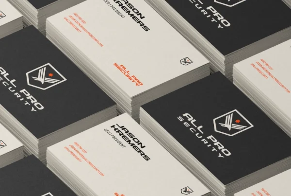Stacks of black and white business cards for “All Pro Security” are arranged in a grid. Some cards show the logo and company name, while others display contact details—similar to designs seen at Pioneer Valley Dental.