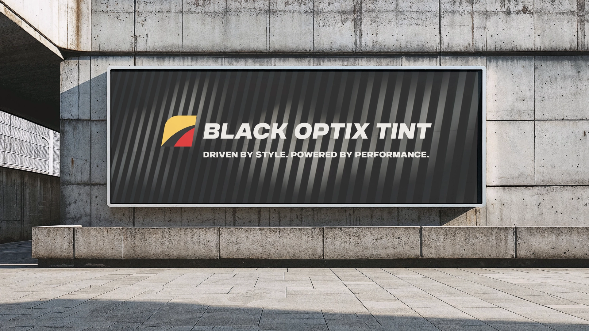 A large outdoor billboard displays the BLACK OPTIX TINT logo with the tagline Driven by style. Powered by performance. on a dark, striped background, mounted on a concrete wall.