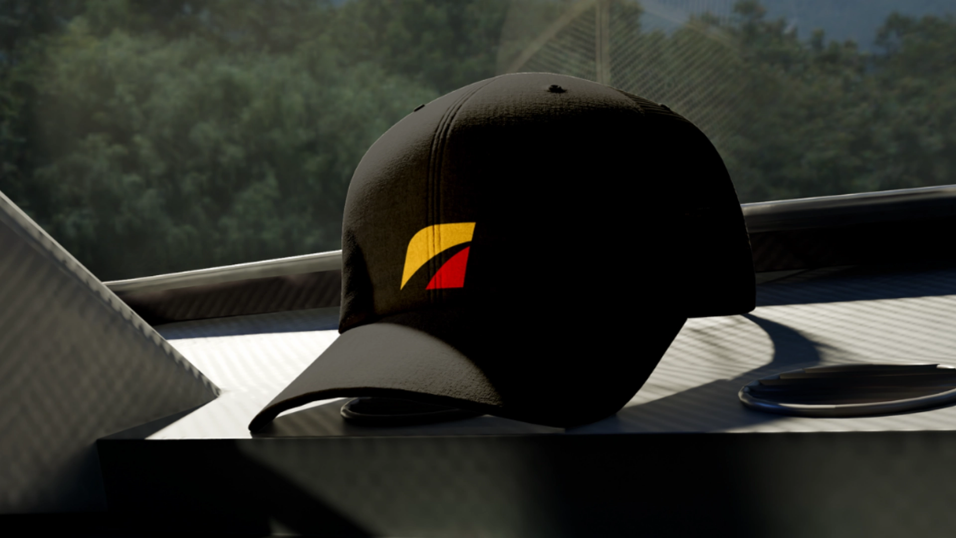 A black baseball cap with a yellow and red geometric logo sits on a metallic surface with blurred green foliage visible in the background.