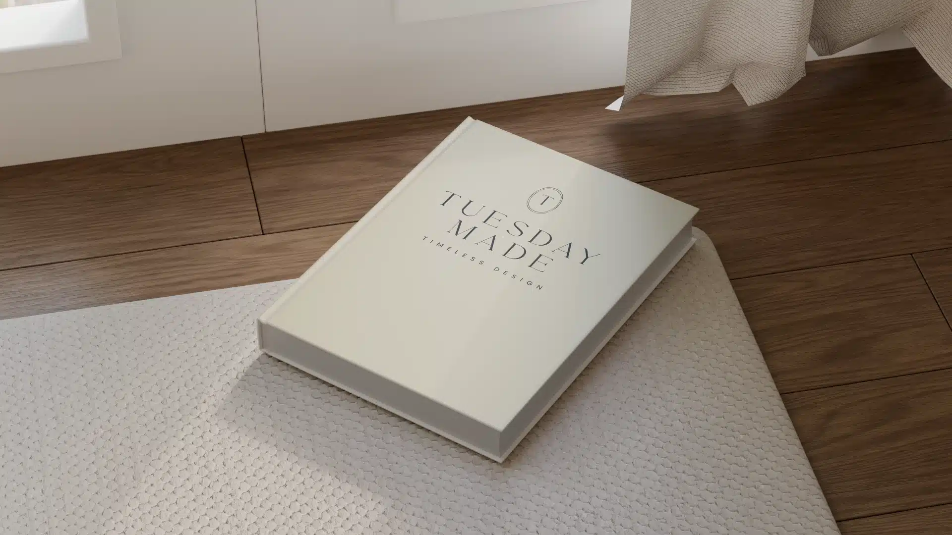 A closed book titled Tuesday Made: Timeless Design rests on a light textured rug next to a wooden floor and a curtain in soft natural light.